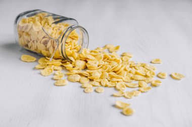 Beyaz ahşap yüzeyde cam bir kavanozda mısır gevreği. Metnin için yer.