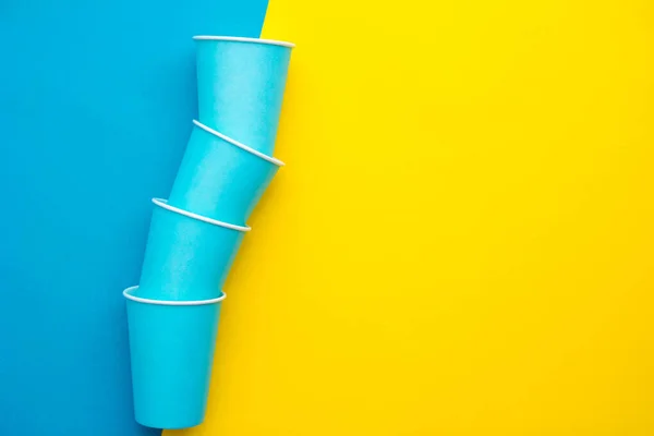 黄色の背景に青い紙使い捨てカップのピラミッド パーティーの準備を テキストのコピー 空のスペース — ストック写真