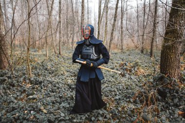 Shinai bambu kılıcıyla orman arka planında Kendo çalışan bir adam. Metin veya reklam için yer.