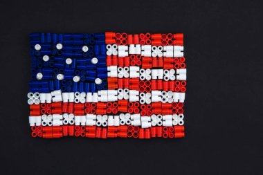 Siyah kağıtta ABD bayrağını oluşturan renkli plastik tuğlalar. Oyuncaklar için küçük, parlak yedek parçalar. Üst görünüm