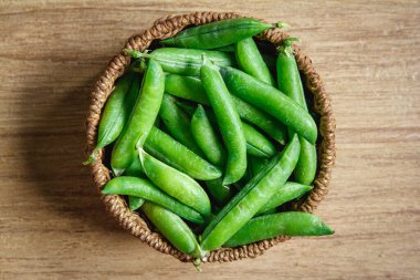 Bezelye hasadı ahşap bir arka planda yuvarlak bir hasır sepetin içinde yatıyor. Üst Manzara. Kopyala, metin için boşluk.