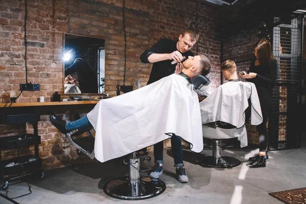 Los peluqueros cortan a sus clientes en la peluquería. Concepto de publicidad y peluquería — Foto de Stock