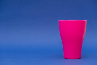 Mavi arka planda pembe plastik bardak. Minimalist stil. Kopyala, metin için boşluk.