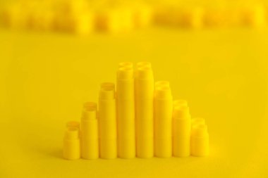 Sarı arka planda piramit şeklinde sarı plastik yapı taşları. Plastik yapı taşlarının arka planı. Oyuncaklar için küçük, parlak yedek parçalar. Kopyala, metin için boşluk.