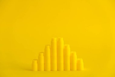 Sarı arka planda piramit şeklinde sarı plastik yapı taşları. Plastik yapı taşlarının arka planı. Oyuncaklar için küçük, parlak yedek parçalar. Kopyala, metin için boşluk.