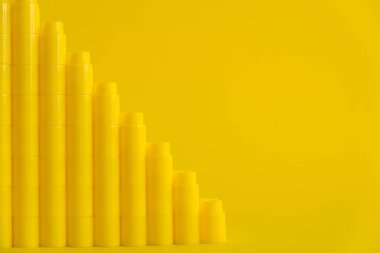 Sarı arka planda piramit şeklinde sarı plastik yapı taşları. Plastik yapı taşlarının arka planı. Oyuncaklar için küçük, parlak yedek parçalar. Kopyala, metin için boşluk.