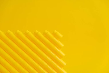 Sarı arka planda piramit şeklinde sarı plastik yapı taşları. Plastik yapı taşlarının arka planı. Oyuncaklar için küçük, parlak yedek parçalar. Kopyala, metin için boşluk.