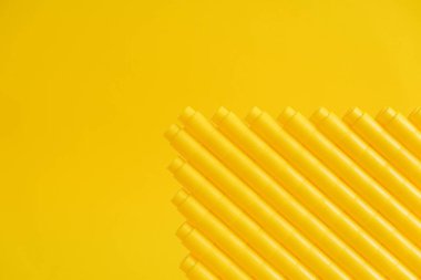 Sarı arka planda piramit şeklinde sarı plastik yapı taşları. Plastik yapı taşlarının arka planı. Oyuncaklar için küçük, parlak yedek parçalar. Kopyala, metin için boşluk.