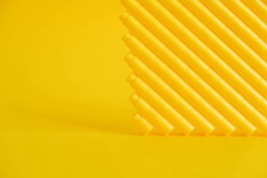 Sarı arka planda piramit şeklinde sarı plastik yapı taşları. Plastik yapı taşlarının arka planı. Oyuncaklar için küçük, parlak yedek parçalar. Kopyala, metin için boşluk.