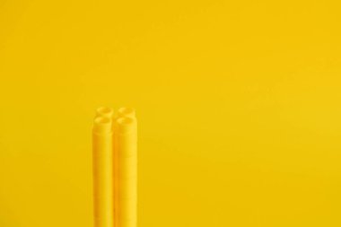 Sarı arka planda bir kule şeklinde sarı plastik yapı taşları. Plastik yapı taşlarının arka planı. Oyuncaklar için küçük, parlak yedek parçalar. Kopyala, metin için boşluk.