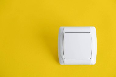 Sarı arka planda beyaz elektro anahtarı. Üst Manzara. Minimalist stil. Kopyala, metin için boşluk.