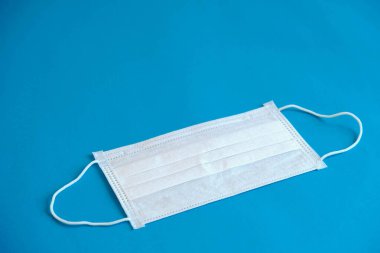 Mavi arka planda tıbbi maske. Bakterilerin prosedür maskesi. Koruma konsepti. Üst Manzara. Kopyala, metin için boşluk.