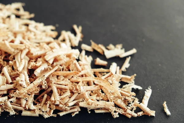 Wood shavings on black background. Background of fresh wood shavings. Copy, empty space for text.