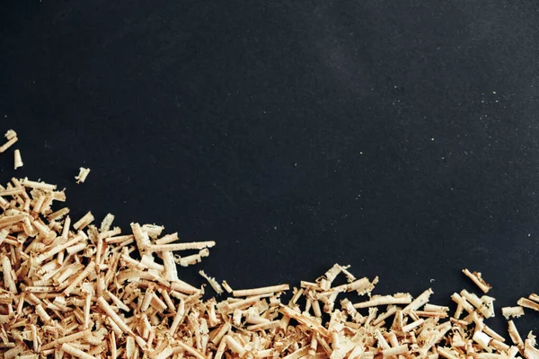 Wood shavings on black background. Background of fresh wood shavings. Copy, empty space for text.