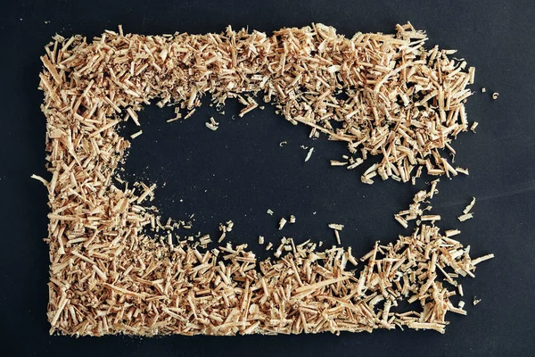 Wood shavings on black background. Background of fresh wood shavings. Copy, empty space for text.