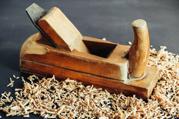 Old hand plane and wood shavings on black background. Old woodworking hand too on a black background. Copy, empty space for text.