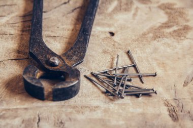 Ahşap arka planda paslı kıskaçlar ve çiviler. Kopyala, metin için boşluk.