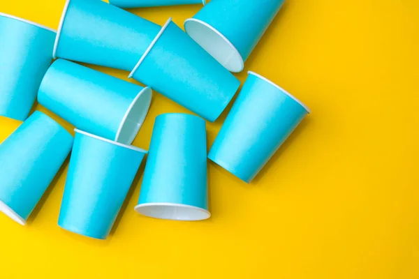 黄色の背景に青紙使い捨てカップからのパターン パーティーの準備を 最上階だ ミニマリストスタイル テキストのコピー 空のスペース — ストック写真