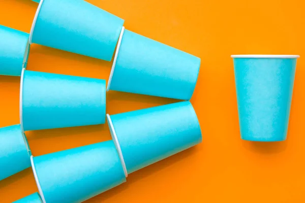オレンジの背景に青紙の使い捨てカップからパターン パーティーの準備を 最上階だ ミニマリストスタイル テキストのコピー 空のスペース — ストック写真
