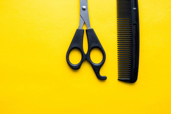 Scissors and comb for hairdresser on a yellow background. Top view. Copy, empty space for text.