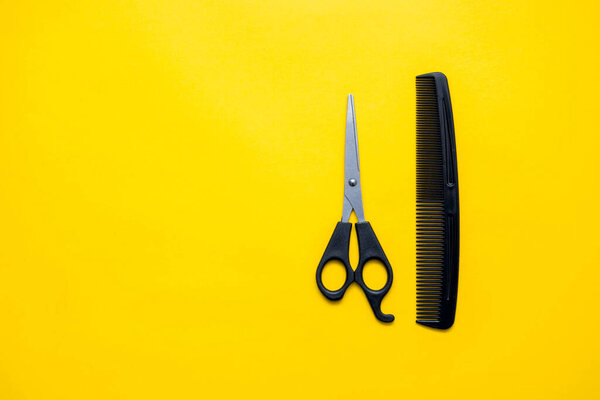 Scissors and comb for hairdresser on a yellow background. Top view. Copy, empty space for text.