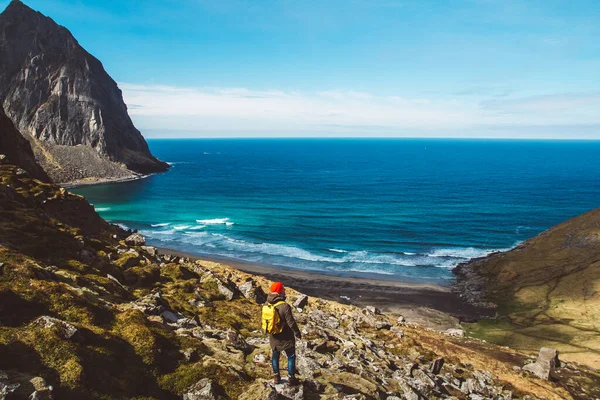 Traveler man stand on cliff edge on the background of mountains, rocks and sea. Place for text or advertising.