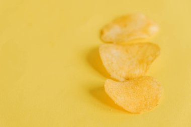 Sarı arka planda üç patates cipsi. Üst Manzara. Kopyala, metin için boşluk.