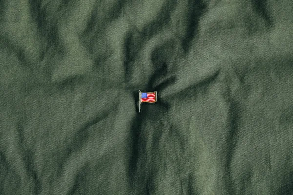 USA flag pin badge on green fabric background. Top view. Copy, empty space for text.