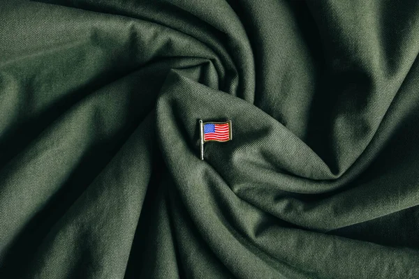 USA flag pin badge on green fabric background. Top view. Copy, empty space for text.