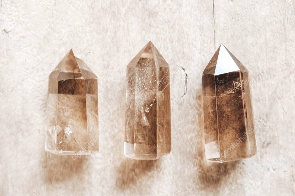 Three smoky natural quartz crystals on wooden background. Top view. Copy, empty space for text.