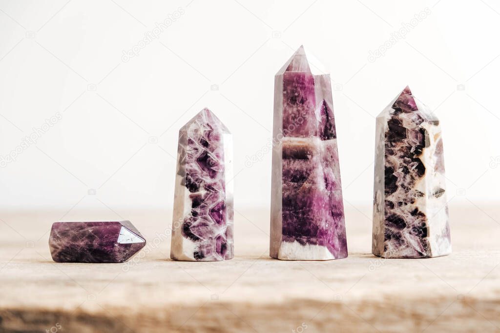 Amethyst polished crystal point on a wooden table. Copy, empty space for text.
