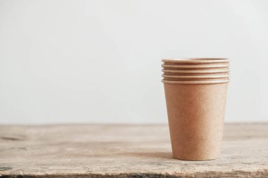 Tek kullanımlık kağıt bardaklar ahşap arka planda çevre dostu tek kullanımlık sofra takımı. Sıfır atık. Kopyala, metin için boşluk.