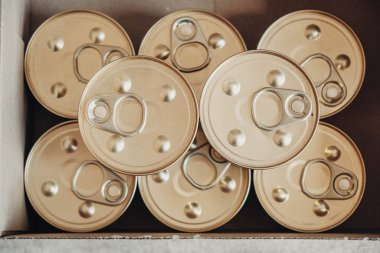 Karton bir arka planda metal kapaklı konserve yiyecekler. Üst Manzara. Kopyala, metin için boşluk.