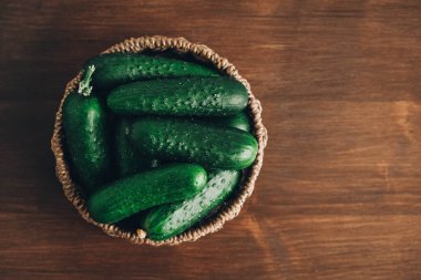 Tahta bir arka planda sepetteki taze yeşil salatalıklar. Üst Manzara. Kopyala, metin için boşluk.