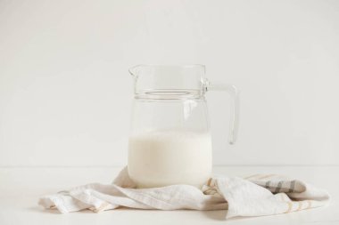 Süt ve peçeteyle beyaz bir masada cam sürahi. Kopyala, metin için boşluk.