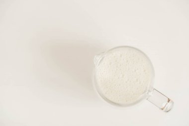 Sütlü cam sürahi beyaz bir masada. Üst Manzara. Kopyala, metin için boşluk.