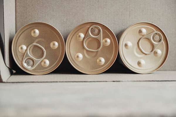 Metal closed canned food on a cardboard background. Top view. Copy, empty space for text.