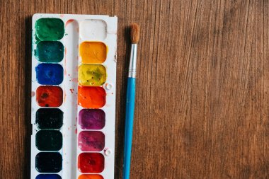 Koyu ahşap arka planda boyamak için fırçayla boyanmış suluboya tabloları. Üst Manzara. Kopyala, metin için boşluk.