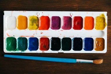 Koyu ahşap arka planda boyamak için fırçayla boyanmış suluboya tabloları. Üst Manzara. Kopyala, metin için boşluk.