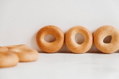 Beyaz ahşap arka planda küçük yuvarlak simitler. Kopyala, metin için boşluk.