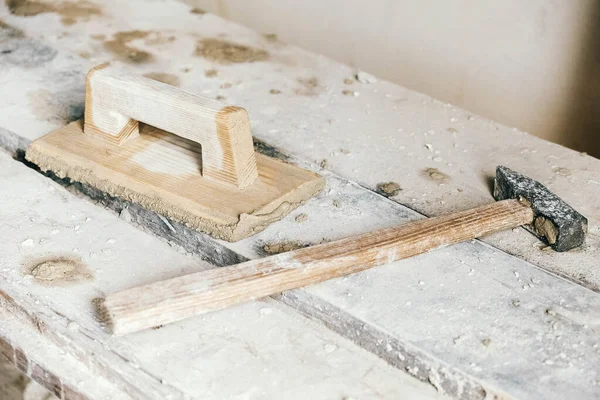 Old construction tools for plaster on vintage wood bench. Trowels and other masonry tools. Copy, empty space for text.