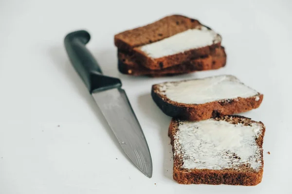 Krojony Brązowego Chleba Masłem Nożem Kuchennym Białym Drewnianym Tle Widok — Zdjęcie stockowe