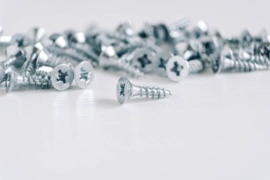 Beyaz ahşap arka planda tahta vidaları için metal dokunuşlar. İnşaat malzemeleri konsepti. Kopyala, metin için boşluk.