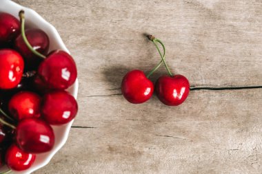 Tahta zemin üzerinde beyaz bir tabakta taze olgun kirazlar. Üst Manzara. Kopyala, metin için boşluk.