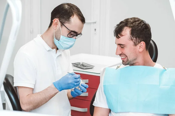 Dentist consults and talks to the male patient on the dentist\'s chair. Copy, empty space for text.