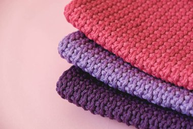 Pembe arka planda pembe, kırmızı ve mor renkli ipliklerden örülmüş bir yığın malzeme. Üst Manzara. Kopyala, metin için boşluk.