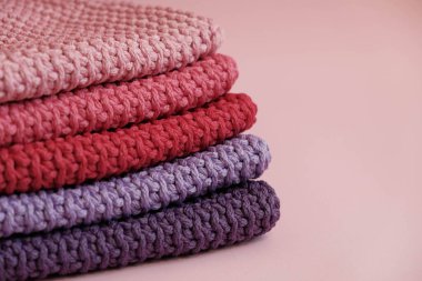Pembe arka planda pembe, kırmızı ve mor renkli ipliklerden örülmüş bir yığın malzeme. Üst Manzara. Kopyala, metin için boşluk.