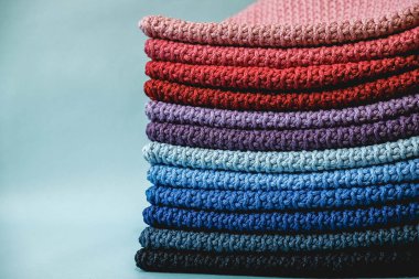 Mavi arka plandaki çok renkli ipliklerden örülmüş bir yığın malzeme. Kopyala, metin için boşluk.