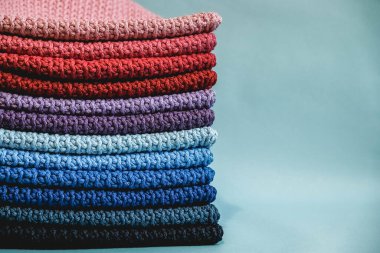 Mavi arka plandaki çok renkli ipliklerden örülmüş bir yığın malzeme. Kopyala, metin için boşluk.