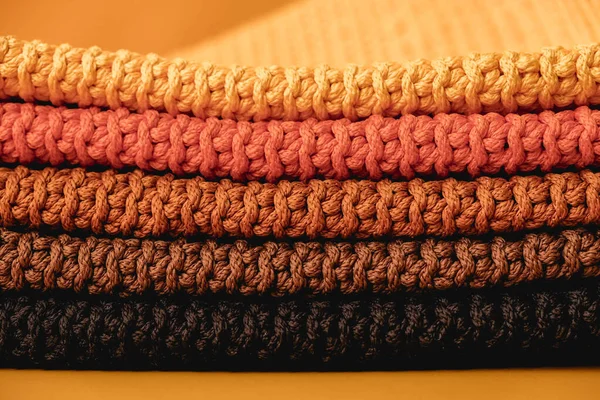 Stock image Stack of knitted material from threads of yellow, orange, brown colors on a orange background. Copy, empty space for text.